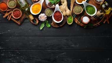 Kase ve kaşık büyük baharat ve ot toplama. Hint baharatları. Siyah ahşap bir arka plan üzerinde. Üstte görüntü.