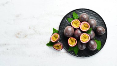 Beyaz ahşap arka plan üzerinde bir yaprak ile Passion meyve. Tropikal Meyveler. Üst te. Metin için boş alan.