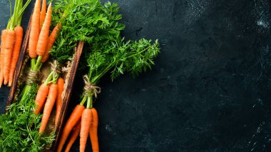 Siyah taş arka planda taze havuç. Üst görünüm. Metniniz için boş alan.
