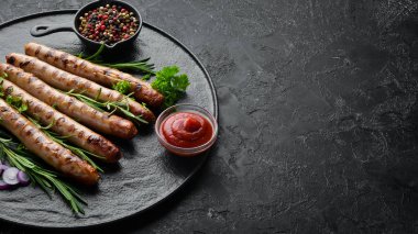 Siyah taş tabakta domates soslu ızgara sosisler. Barbekü. Üst görünüm. Ücretsiz kopyalama alanı.
