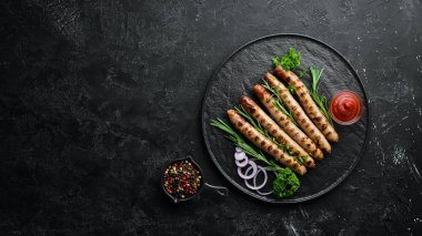 Siyah taş tabakta domates soslu ızgara sosisler. Barbekü. Üst görünüm. Ücretsiz kopyalama alanı.