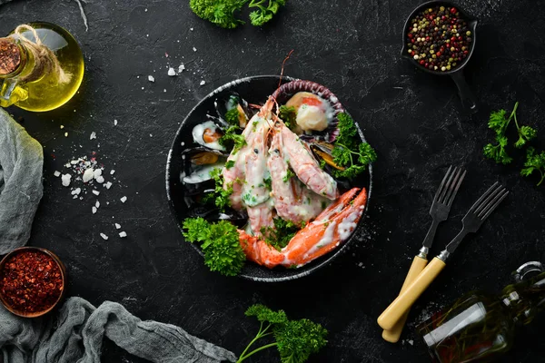 Siyah taş tabaktabaktabaktabaktabaktabaktabaktabaktabakta kremalı soslu haşlanmış deniz ürünleri. Deniz ürünleri, karides, kabuklu deniz ürünleri, ıstakoz. Üst te. Ücretsiz kopyalama alanı.