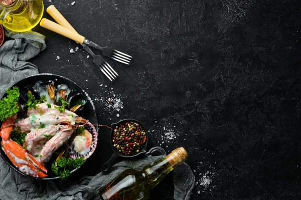 Siyah taş tabaktabaktabaktabaktabaktabaktabaktabaktabakta kremalı soslu haşlanmış deniz ürünleri. Deniz ürünleri, karides, kabuklu deniz ürünleri, ıstakoz. Üst te. Ücretsiz kopyalama alanı.