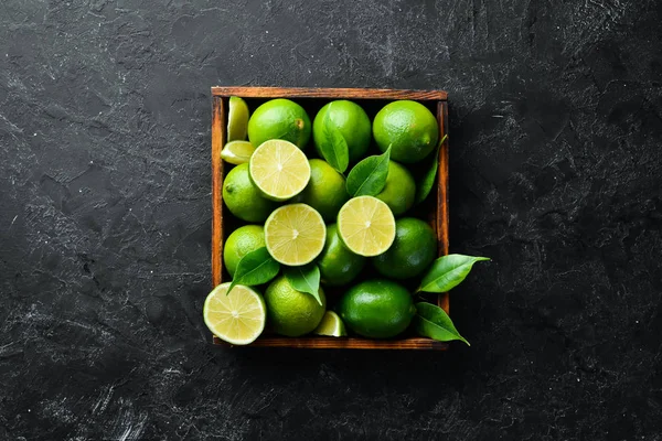 Groene Limoen Een Houten Kist Citrusvruchten Een Zwarte Stenen Achtergrond — Stockfoto