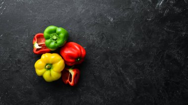 Siyah taş arka plan üzerinde taze renkli kırmızı biber. Üst te. Ücretsiz kopyalama alanı.