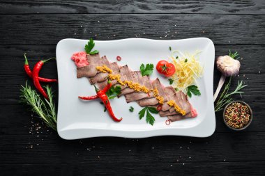 Bir tabakta sebze ve baharat ile haşlanmış dana dili. Restoran yemekleri. Üst te. Metniniz için boş alan.