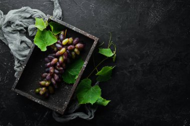 Siyah taş masada yaprakları ile taze kırmızı üzüm. Üst te. Metniniz için boş alan.