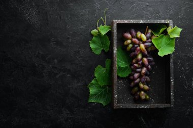 Siyah taş masada yaprakları ile taze kırmızı üzüm. Üst te. Metniniz için boş alan.