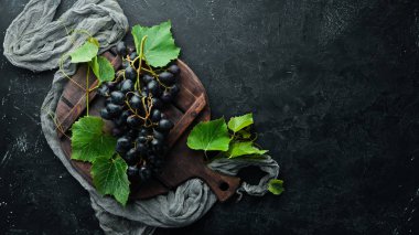 Siyah taş masada yaprakları ile taze kırmızı üzüm. Üst te. Metniniz için boş alan.