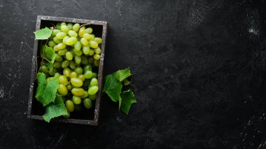 Siyah taş masada yaprakları ile taze yeşil üzüm. Üst te. Metniniz için boş alan.