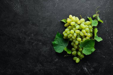 Siyah taş masada yaprakları ile taze yeşil üzüm. Üst te. Metniniz için boş alan.