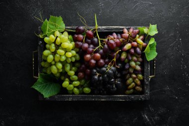 Siyah taş masada yaprakları olan taze üzümler. Üst te. Metniniz için boş alan.