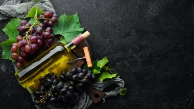 Siyah taş masada bir şişe beyaz şarap ve taze üzüm. Üst te. Metniniz için boş alan.