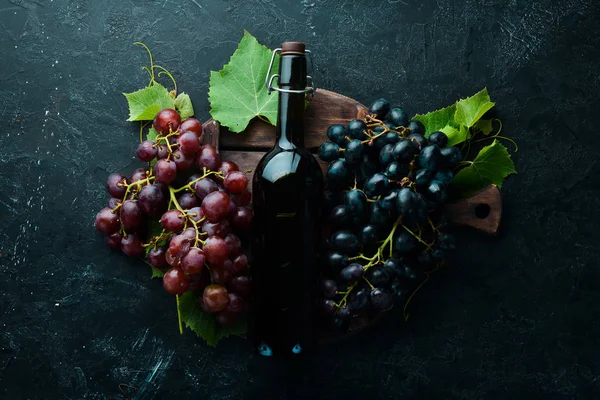 Red wine and fresh grapes on a black stone table. Top view. Free space for your text.