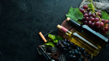 Siyah taş masada bir şişe kırmızı ve beyaz şarap ve üzüm. Üst te. Metniniz için boş alan.