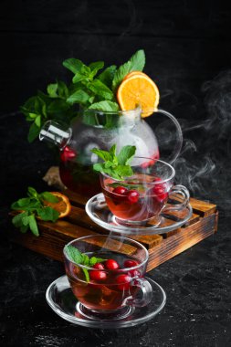 Kızılcık ve nane çayı. Sıcak kış içecekleri. Siyah bir arka plan üzerinde. Üstte görüntü.