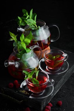 Ahududu ve nane çayı. Sıcak kış içecekleri. Siyah bir arka plan üzerinde. Üstte görüntü.