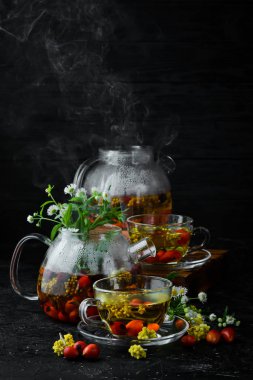 Papatya ve yabani gül çayı. Sıcak kış içecekleri. Siyah bir arka plan üzerinde. Üstte görüntü.