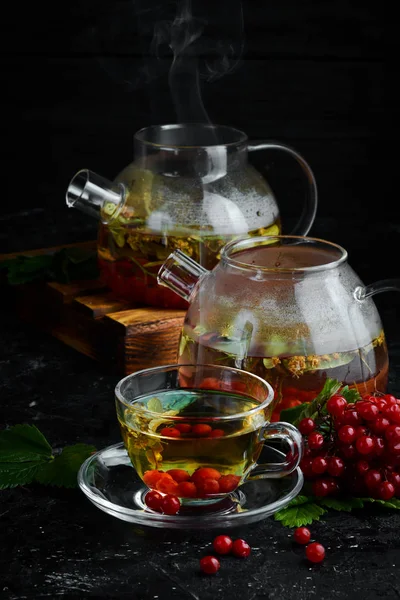 Tea from viburnum and forest herbs. Hot winter drinks. On a black background. Top view.