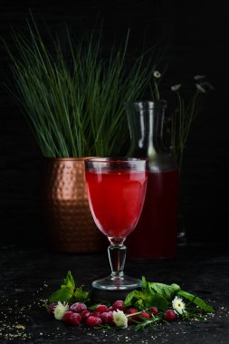 Taze Kızılcık Böğürtlenmorları bardakta. Üst te. Siyah arka planda.