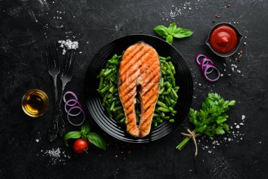 Siyah tabakta yeşil fasulyeli fırında somon bifteği. Üst Manzara. Boş kopyalama alanı.