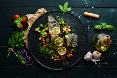 Siyah tabakta sebzeli ve limonlu fırında balık. Üst Manzara. Boş kopyalama alanı.