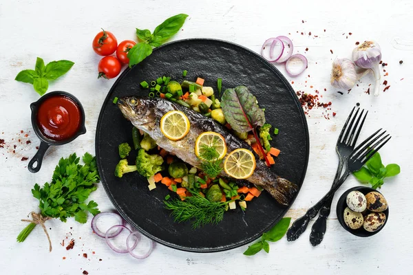 Siyah tabakta sebzeli ve limonlu fırında balık. Üst Manzara. Boş kopyalama alanı.