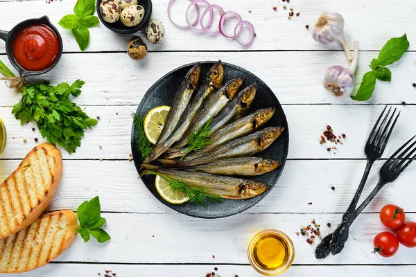 Smoked capelin fish with lemon on a black plate. Top view. Free copy space. — Stock Image Smoked Capelin Fish Lemon Black Plate Top View Free Copy Stock Picture