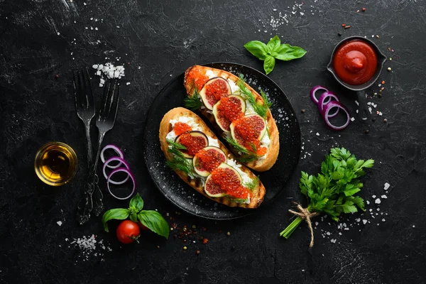 Havyarlı sandviç, beyaz peynir ve siyah tabakta incir. Üst Manzara. Boş kopyalama alanı.