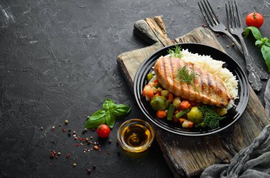 Siyah tabakta pilav ve sebzeli fırında tavuk filetosu. Üst Manzara. Boş kopyalama alanı.