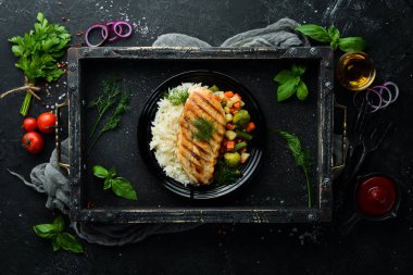 Siyah tabakta pilav ve sebzeli fırında tavuk filetosu. Üst Manzara. Boş kopyalama alanı.