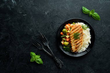 Siyah tabakta pilav ve sebzeli fırında tavuk filetosu. Üst Manzara. Boş kopyalama alanı.