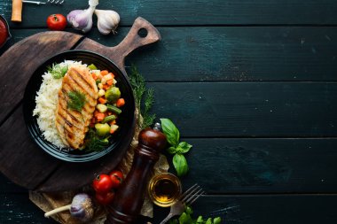 Siyah tabakta pilav ve sebzeli fırında tavuk filetosu. Üst Manzara. Boş kopyalama alanı.