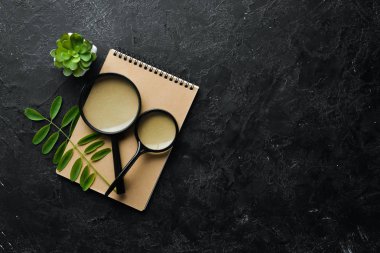 Okumak için büyüteç. Siyah taştan bir arka planda. Üst Manzara. Metnin için boş yer. Düz yatıyordu.