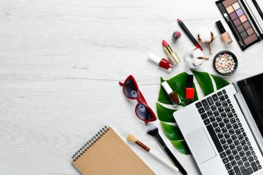 Beyaz ofis masasında kadın kozmetik ürünleri. Laptop, not defteri, ruj, pudra, tarak, kadın mücevherleri. Üst Manzara. Metnin için boş yer. Düz yatıyordu.