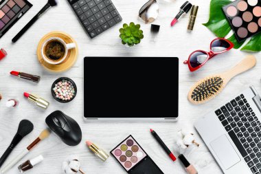Beyaz ofis masasında kadın kozmetik ürünleri. Laptop, not defteri, ruj, pudra, tarak, kadın mücevherleri. Üst Manzara. Metnin için boş yer. Düz yatıyordu.