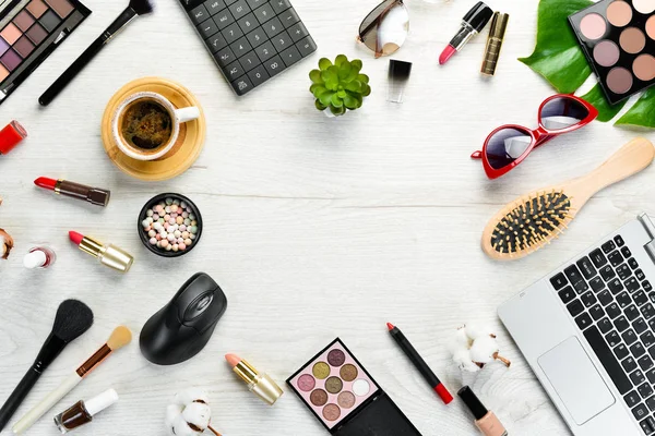 Beyaz ofis masasında kadın kozmetik ürünleri. Laptop, not defteri, ruj, pudra, tarak, kadın mücevherleri. Üst Manzara. Metnin için boş yer. Düz yatıyordu.