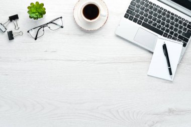 Boş defterli beyaz ofis masası, bilgisayar klavyesi ve ofis malzemeleri. Kopyalama alanı olan üst görünüm, düz yatay.