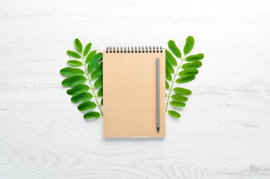 Not defteri ve ofis malzemeleriyle dolu beyaz ofis masası. Kopyalama alanı olan üst görünüm, düz yatay.