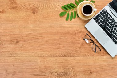 Laptop, hesap makinesi, kahve ve kameralı kahverengi ofis masası. Üst Manzara. Metnin için boş yer. Düz yatıyordu.
