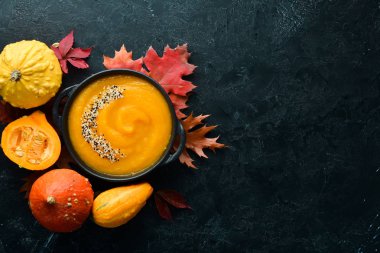Sonbahar kompozisyonu: kabaklı balkabağı çorbası ve renkli sonbahar yaprakları. Düz yat. Beyaz ahşap bir arka planda. Üst Manzara. Metnin için boş yer.