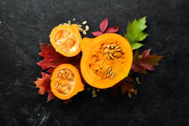 Sonbahar sebzeleri. Balkabağı çekirdekli balkabağı ve sonbahar yapraklı. Düz yat. Siyah taştan bir arka planda. Üst Manzara. Metnin için boş yer.