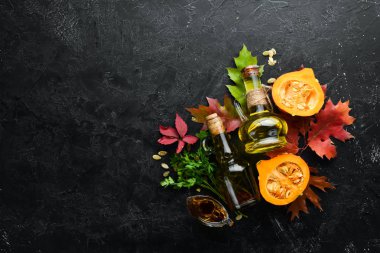 Balkabağı yağı ve balkabağı. Sonbahar sebzeleri. Düz yat. Siyah taştan bir arka planda. Üst Manzara. Metnin için boş yer.