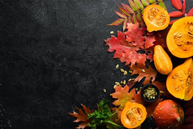 Sonbahar arka planında kahve, balkabağı, sonbahar yaprakları ve tohumlar var. Düz yat. Siyah taştan bir arka planda. Üst Manzara. Metnin için boş yer.