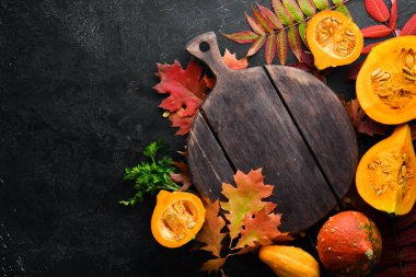 Sonbahar arka planında kahve, balkabağı, sonbahar yaprakları ve tohumlar var. Düz yat. Siyah taştan bir arka planda. Üst Manzara. Metnin için boş yer.