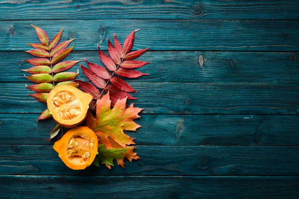 Autumn vegetables. Colored pumpkins with autumn leaves. flat lay. On a blue wooden background. Top view. Free space for your text.
