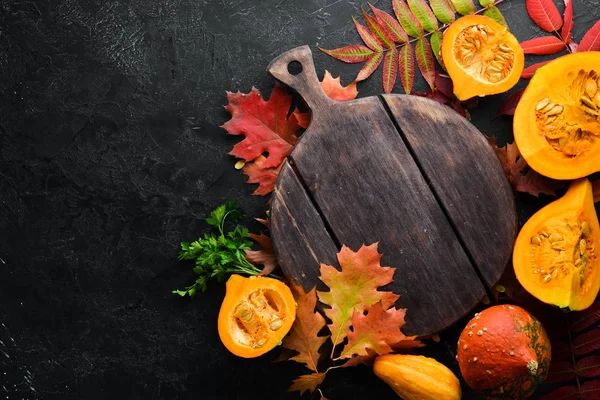 Autumn background with coffee, pumpkin, autumn leaves and seeds. flat lay. On a black stone background. Top view. Free space for your text.
