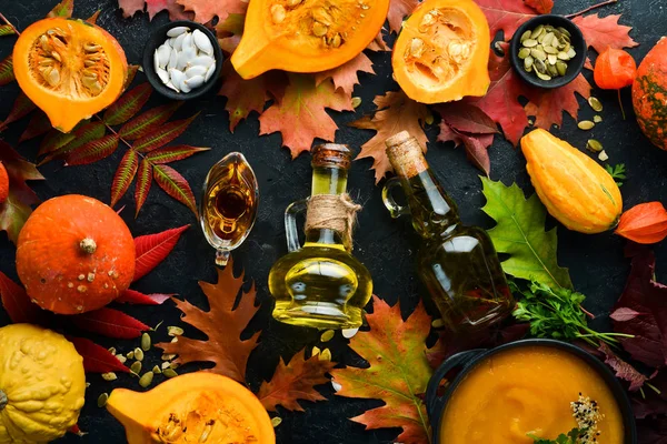 Autumn background with coffee, pumpkin, autumn leaves and seeds. flat lay. On a black stone background. Top view. Free space for your text.