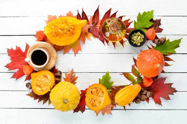 Autumn background with coffee, pumpkin, autumn leaves. flat lay. On a white wooden background. Top view. Free space for your text.