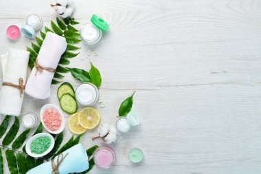 Spa mı? Havlular, yüz kremi, tropik yapraklar. Beyaz ahşap bir arka planda. Düz yatıyordu.
